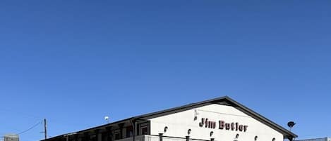 A two-story building with the name 'Jim Butler' on the facade, featuring a balcony on the upper level and a flat roof.