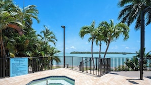 A pool area with a hot tub, surrounded by palm trees and a view of the ocean. - 2B/2B HARBOUR POINTE CONDO 715 ON THE BAY, FISHING DOCK, WALK TO BEACH! (Fort Myers Beach)