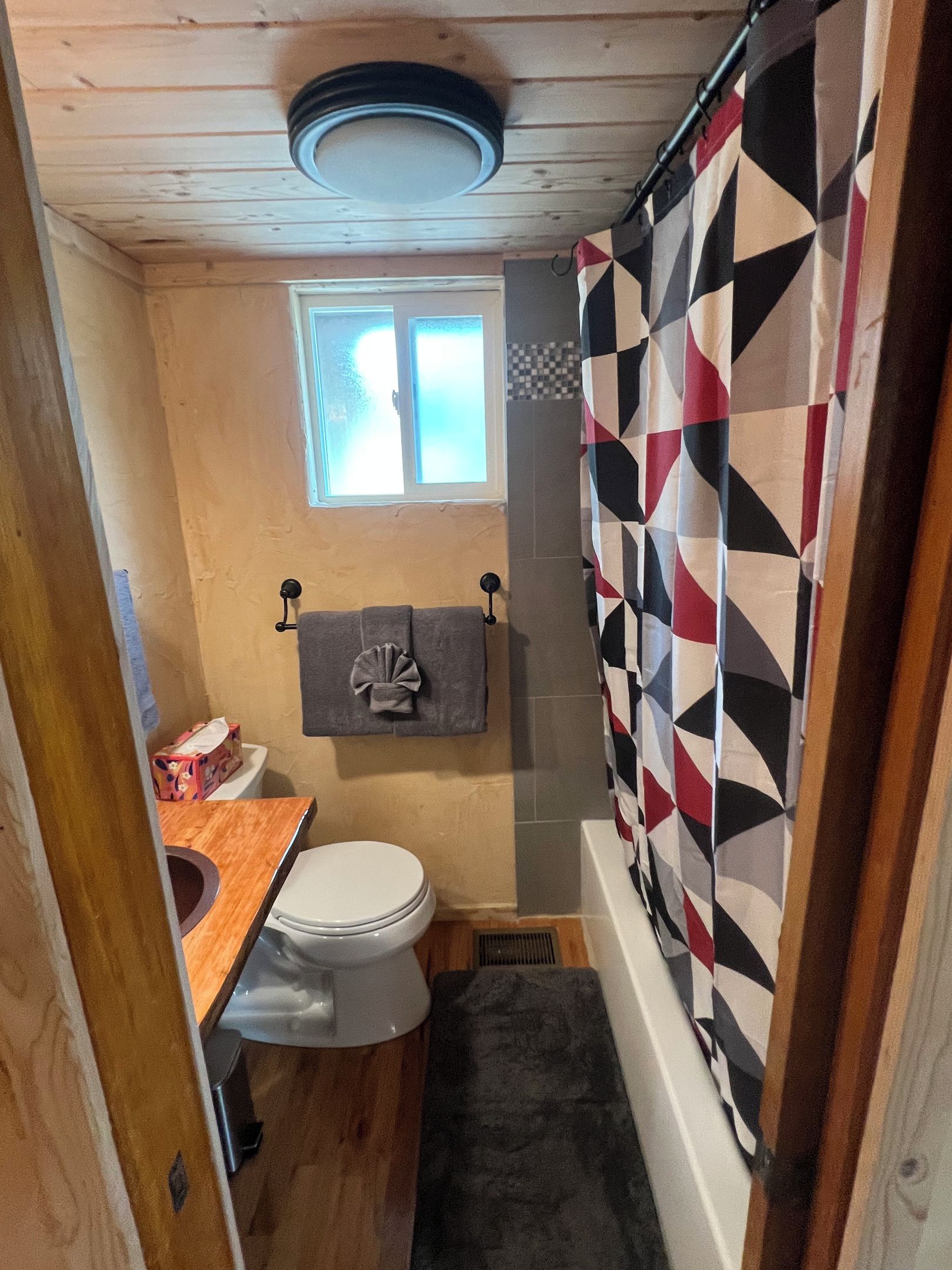 Une petite salle de bain comprenant des toilettes, un porte-serviettes, une fenêtre et un rideau de douche.