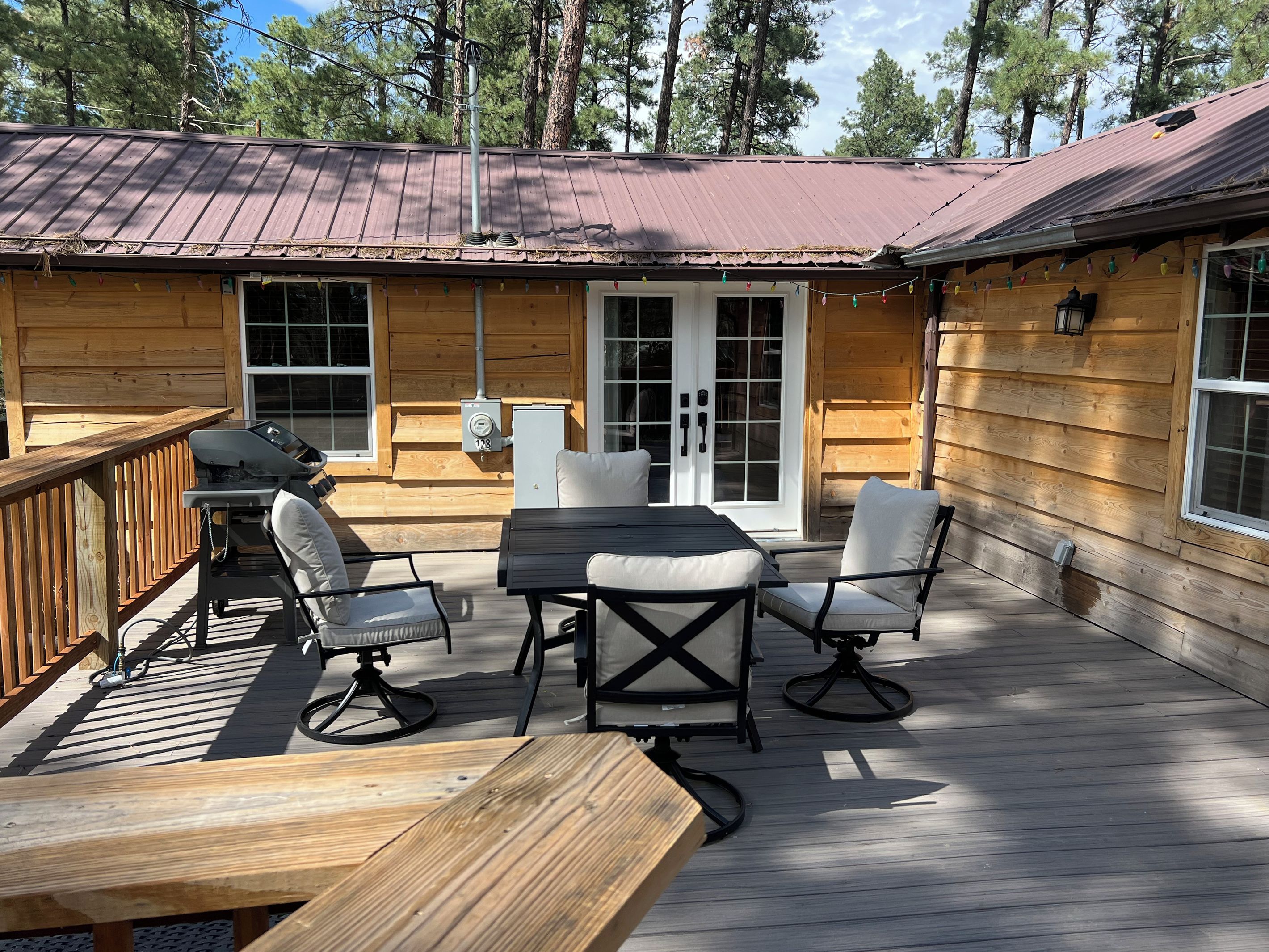 Une terrasse en bois avec des meubles d’extérieur, notamment une table et des chaises, ainsi qu’un barbecue.