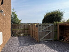 A gravel driveway leading to a wooden gate, a wooden shed with a roof, and a brick wall. - Beautiful 3-bedroom house. Sea view.  40 mins from Edinburgh. Dog friendly. (Burntisland)