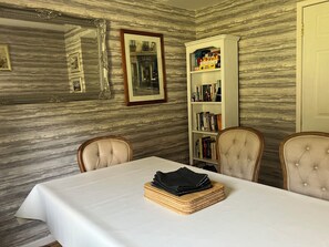 Ein Essbereich mit einer Wand im Marmor-Look, einem weißen Tisch und einem Bücherregal mit Büchern und einer 'Doo Bingo'-Box.