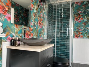 Un bagno con doccia, un lavabo con una bacinella decorativa e un water.
