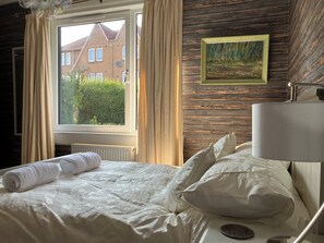 A hotel room with a bed, a window with curtains, a painting on the wall, and a lamp. - Beautiful 3-bedroom house. Sea view.  40 mins from Edinburgh. Dog friendly. (Burntisland)