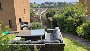 A backyard with a wicker sofa, a barbecue grill, and a wooden shed. - Beautiful 3-bedroom house. Sea view.  40 mins from Edinburgh. Dog friendly. (Burntisland)