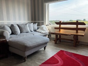A living room with a grey sofa, a red rug, and a wooden bench. - Beautiful 3-bedroom house. Sea view.  40 mins from Edinburgh. Dog friendly. (Burntisland)