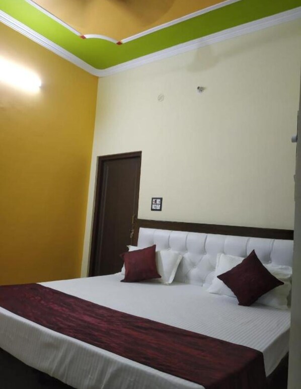 A hotel room with a bed, a door, and a light fixture on the ceiling. - Hotel Awadh Kailash (Bahraich)