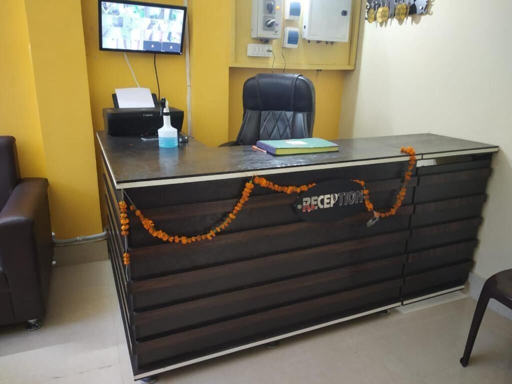 A reception desk with a computer, a chair, and a television mounted on the wall.