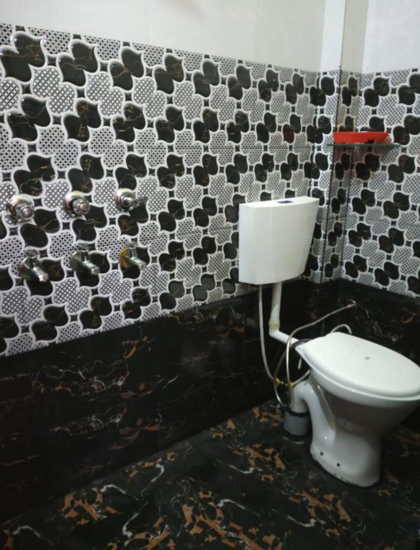 Un baño con inodoro, un sujetapapeles blanco y un papel tapiz estampado.