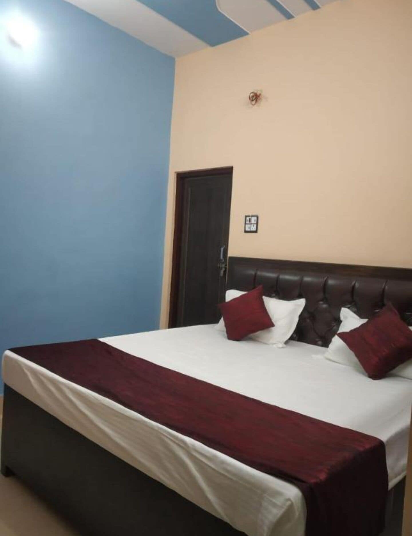 A bedroom with a bed, a door, and a light fixture.