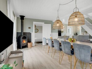 A modern kitchen with a built-in wood stove, a dining area with grey upholstered chairs, and a staircase leading to an upper level. - "Filine" - 100m from the sea by Interhome (Løkken)