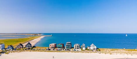 A coastal area with a sandy beach and a row of houses along the shore.