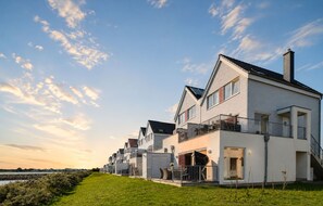 A row of modern houses with balconies, a grassy foreground, and a clear sky. - Vrbo Property (Olpenitz)
