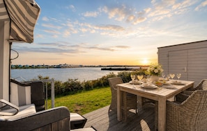 An outdoor dining area with a view of the water and sunset. - Vrbo Property (Olpenitz)