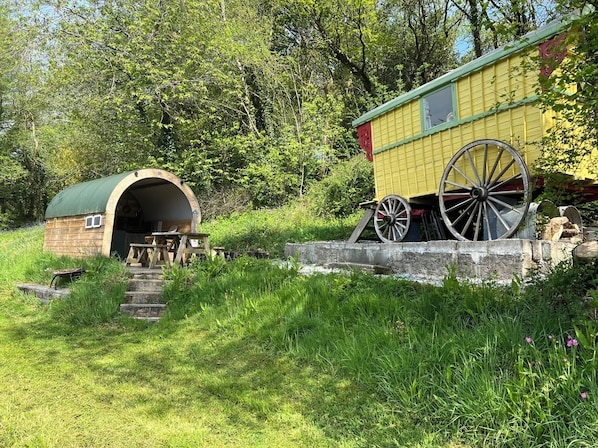A rustic wooden structure with a green roof, a small porch, and a large wooden wheel. - PRUDENCE, pet friendly, character holiday cottage in Ashwater (East Panson)