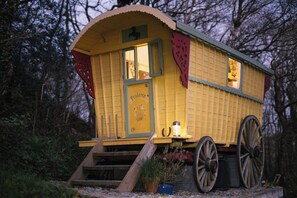 A yellow carriage-like structure with a door, windows, and a small table with a candle. - PRUDENCE, pet friendly, character holiday cottage in Ashwater (East Panson)