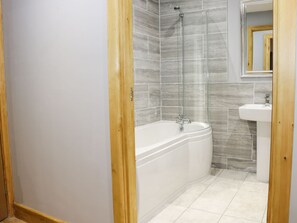 Een badkamer met een bad, douche en wastafel.