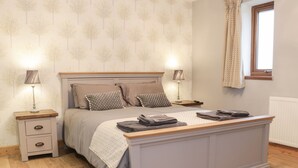A bedroom with a bed, nightstands, lamps, and a window. - WOODMAN'S LODGE, family friendly, with hot tub in Nantwich (Nantwich)
