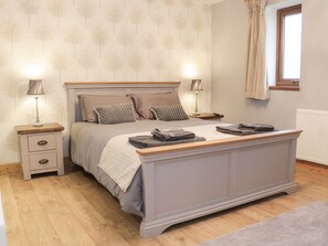 Een slaapkamer met een bed, nachtkastjes, lampen en een raam.