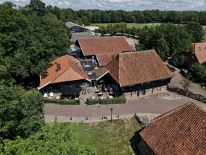 Un bâtiment rural doté d’un toit en pente, entouré d’arbres et de champs ouverts.