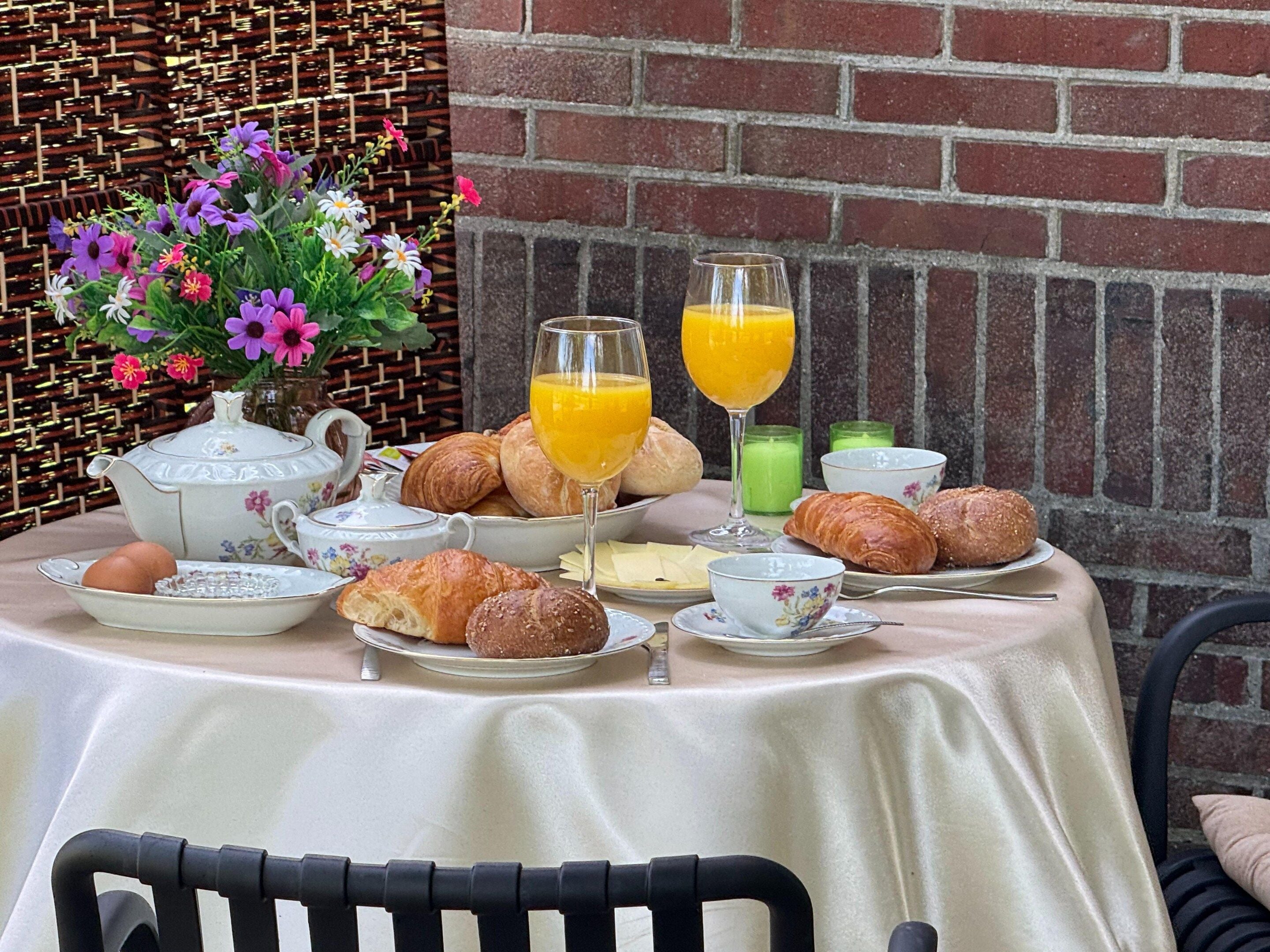 Una mesa de desayuno con croissants, huevos y vasos de jugo.