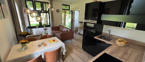Una cocina moderna con comedor, que cuenta con una isla central, iluminación colgante y vistas al exterior.