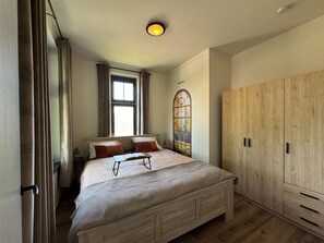 Un dormitorio con cama, ventana, armario y luz de techo.