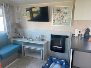A cozy living area with a flat-screen TV, a fireplace, and nautical-themed decorations. - LYONS SUNNYSANDS - SNOWDON SUMMIT 050 in Talybont Near Bangor (Talybont)