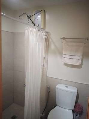 A bathroom with a shower, toilet, and towel rack. - Cozy 1-Studio condo in lovely Cebu City with AC (Cebu City)