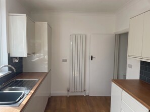 A kitchen with a double sink, white cabinets, a radiator, and a wooden countertop. - SUMMER COTTAGE, pet friendly, with a garden in Rustington (Littlehampton)