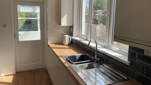 A small kitchen with a window, a sink, and a kettle. - SUMMER COTTAGE, pet friendly, with a garden in Rustington (Littlehampton)