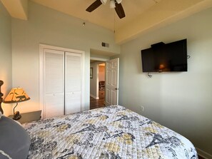 A bedroom with a bed, a ceiling fan, a TV mounted on the wall, and a door leading to another room. - 4th floor condo- amazing views- pool and hot tub (Sugar Mountain)