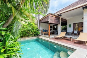 A swimming pool with lounge chairs and a covered patio area. - Just a few min stroll to the Seminyak beach (Bali)