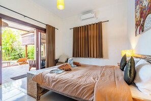 A bedroom with a bed, a window with curtains, a wall-mounted air conditioner, and a painting. - Just a few min stroll to the Seminyak beach (Bali)