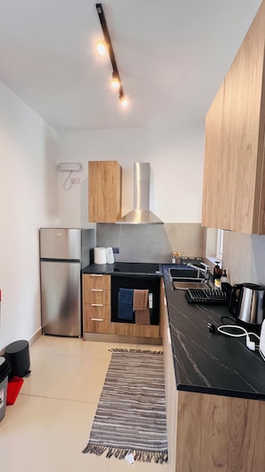 Una cocina moderna con armarios de madera, un refrigerador de acero inoxidable y una encimera negra.