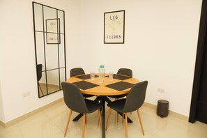 A dining area with a round table, four chairs, and two framed artworks on the wall. - St. Julian's Central Apartment 3 (St. Julian's)