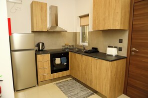 A compact kitchen with wooden cabinets, a built-in oven, a stainless steel refrigerator, and a small window. - St. Julian's Central Apartment 3 (St. Julian's)