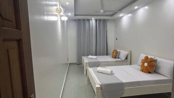 Une chambre d’hôtel avec deux lits, un ventilateur de plafond et une porte.