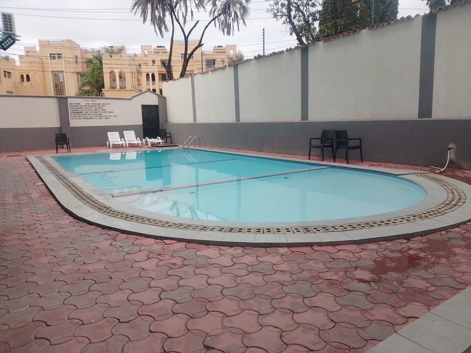Une piscine dotée d’une terrasse carrelée et de chaises longues.