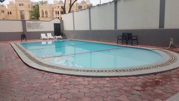 Une piscine dotée d’une terrasse carrelée et de chaises longues.