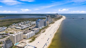 A coastal hotel with multiple buildings, a beach, and a pier extending into the water. - Beachfront condo w oversized balcony, pool & direct beach access (Gulf Shores)