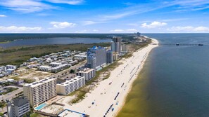 Un hôtel situé sur la côte, composé de plusieurs bâtiments, avec une plage et une jetée qui s’avance dans l’eau.