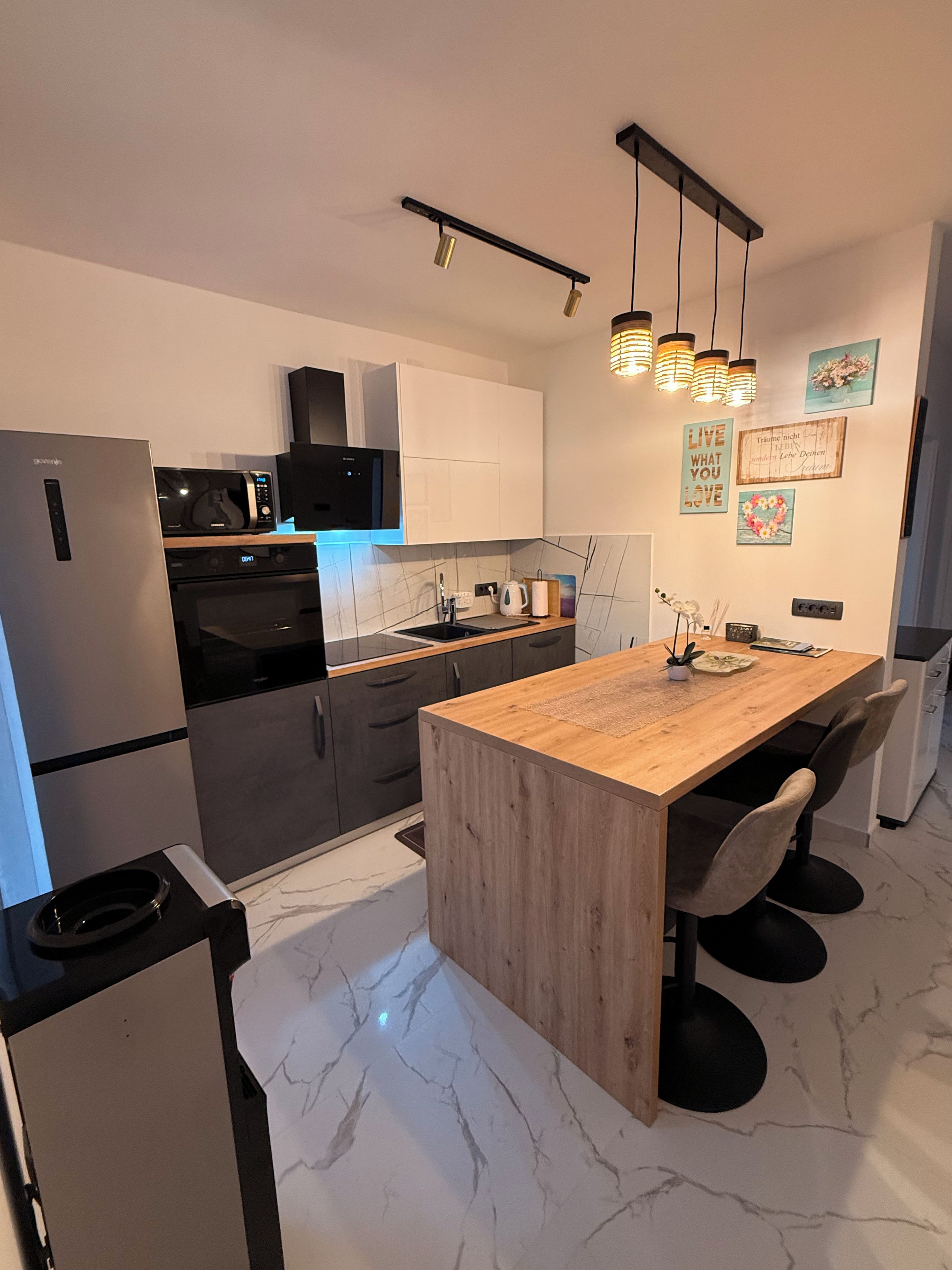 Een moderne keuken met een marmeren aanrechtblad, een inbouwoven en een roestvrijstalen koelkast.
