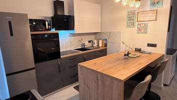 Een moderne keuken met een marmeren aanrechtblad, een inbouwoven en een roestvrijstalen koelkast.