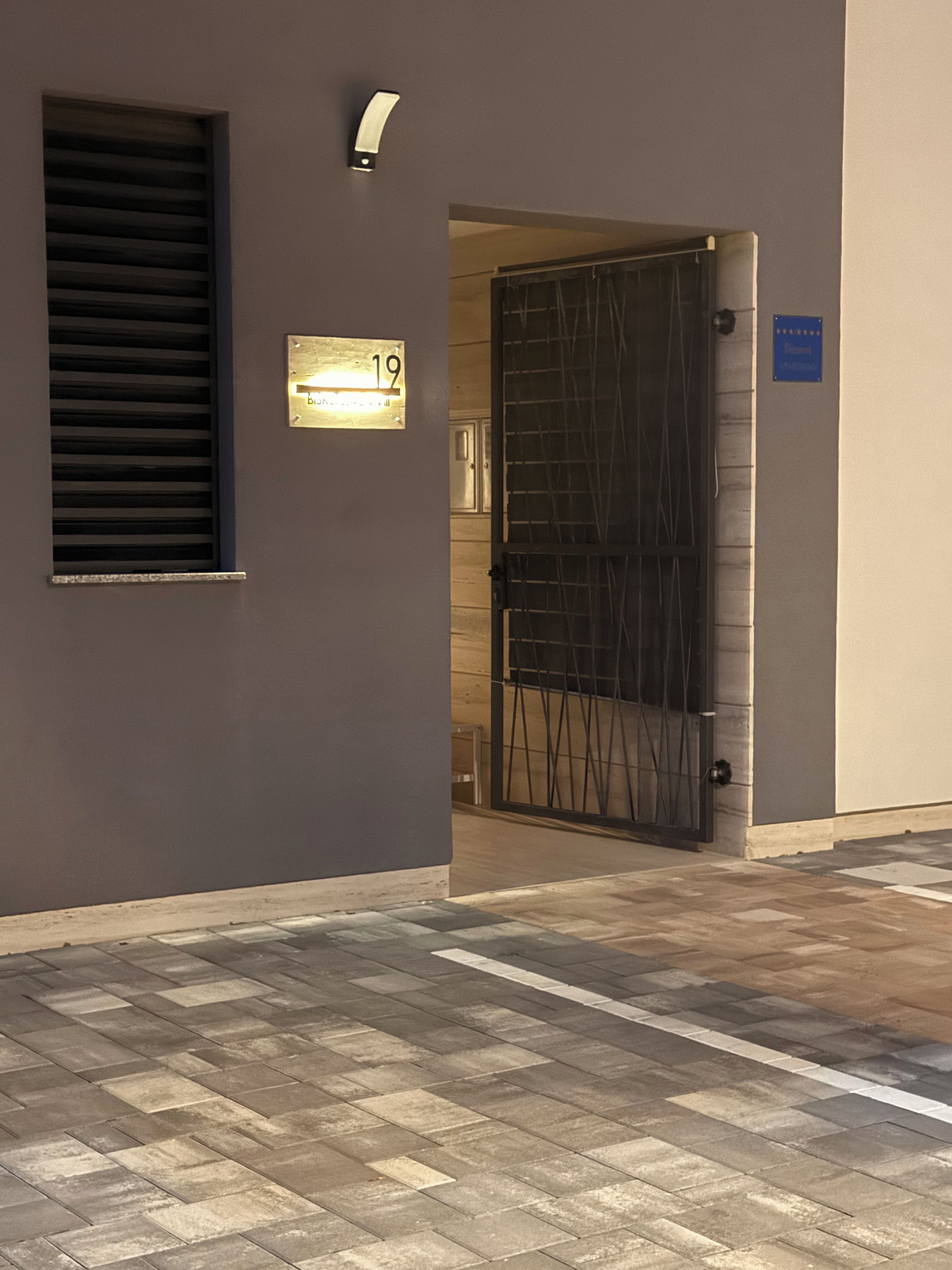 A building entrance with a number plate, a door, and a blue sign.
