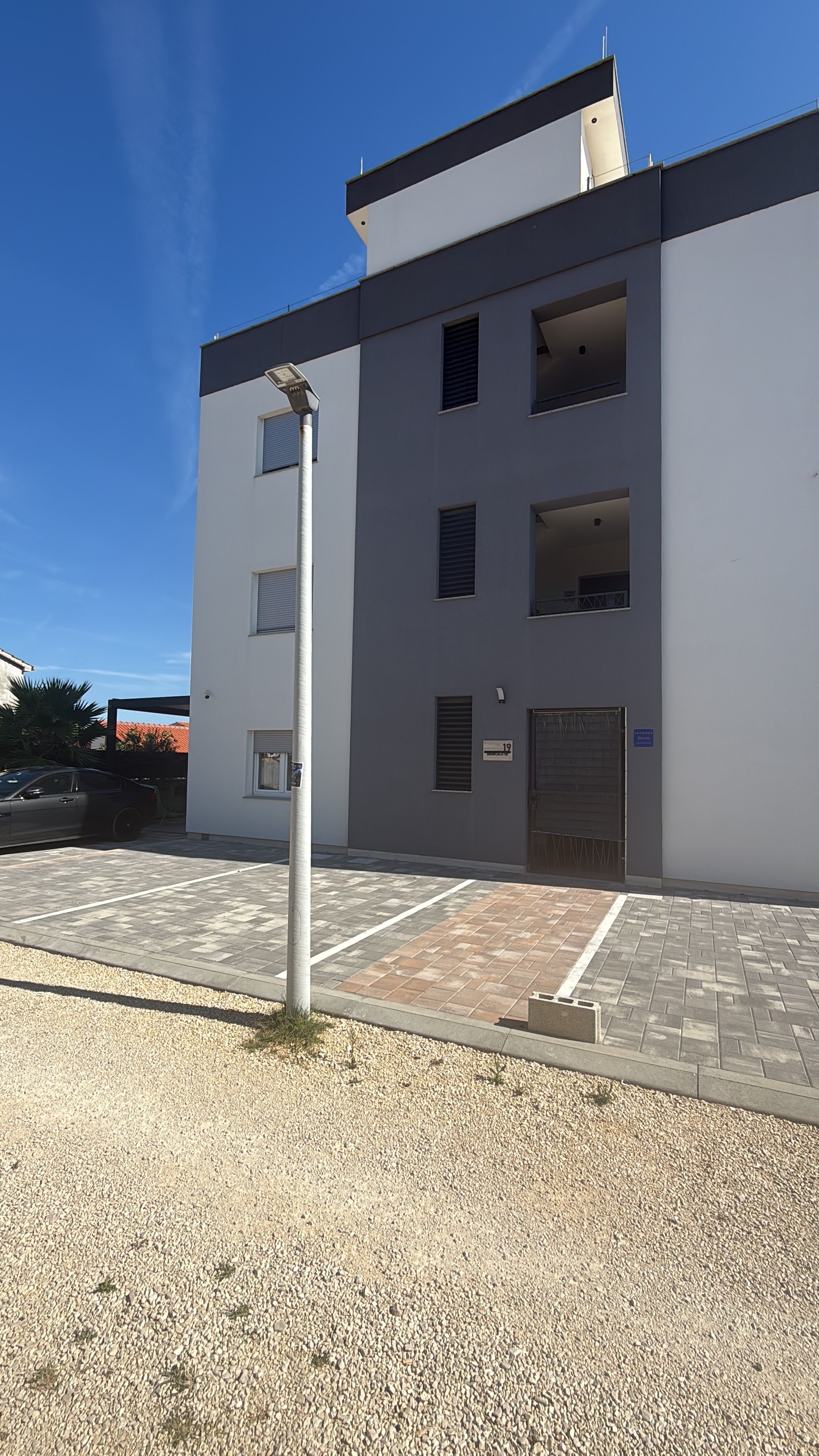 Een modern gebouw met een plat dak, meerdere ramen en een hekwerk.