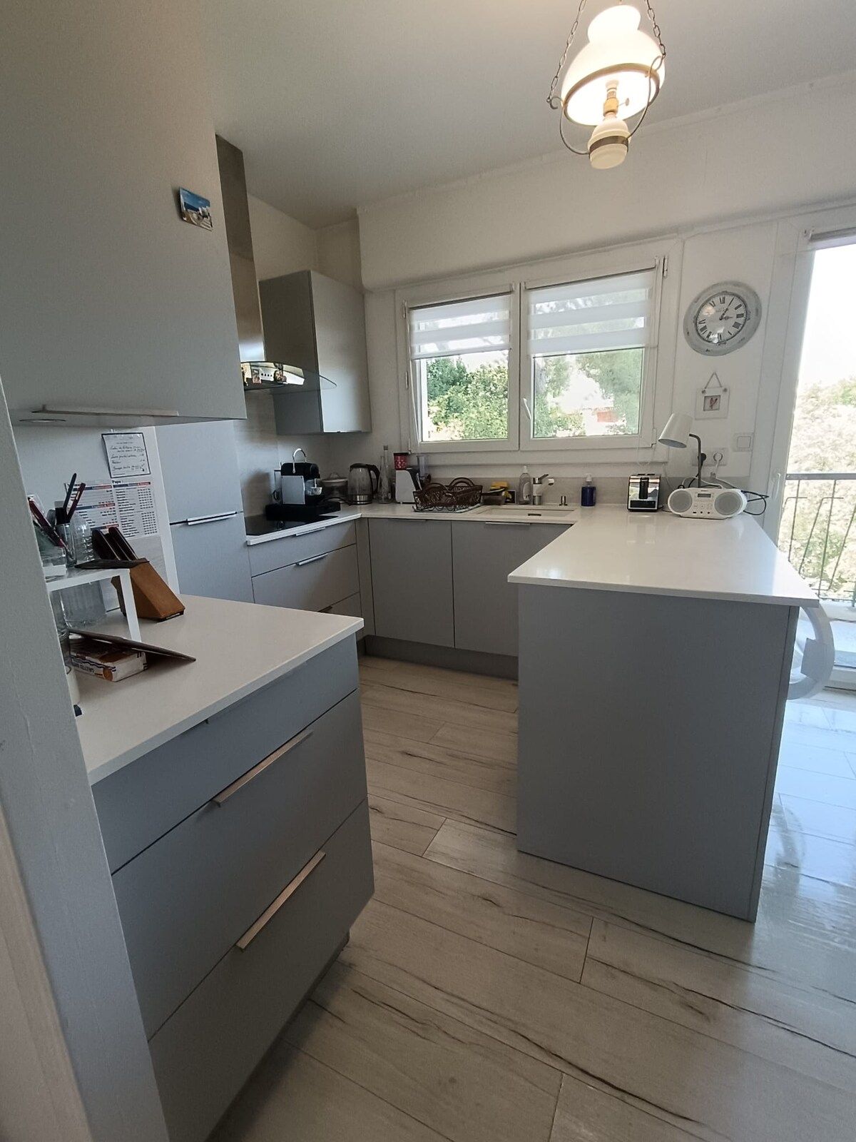 A modern kitchen with grey cabinetry, a central island, and a window providing natural light.