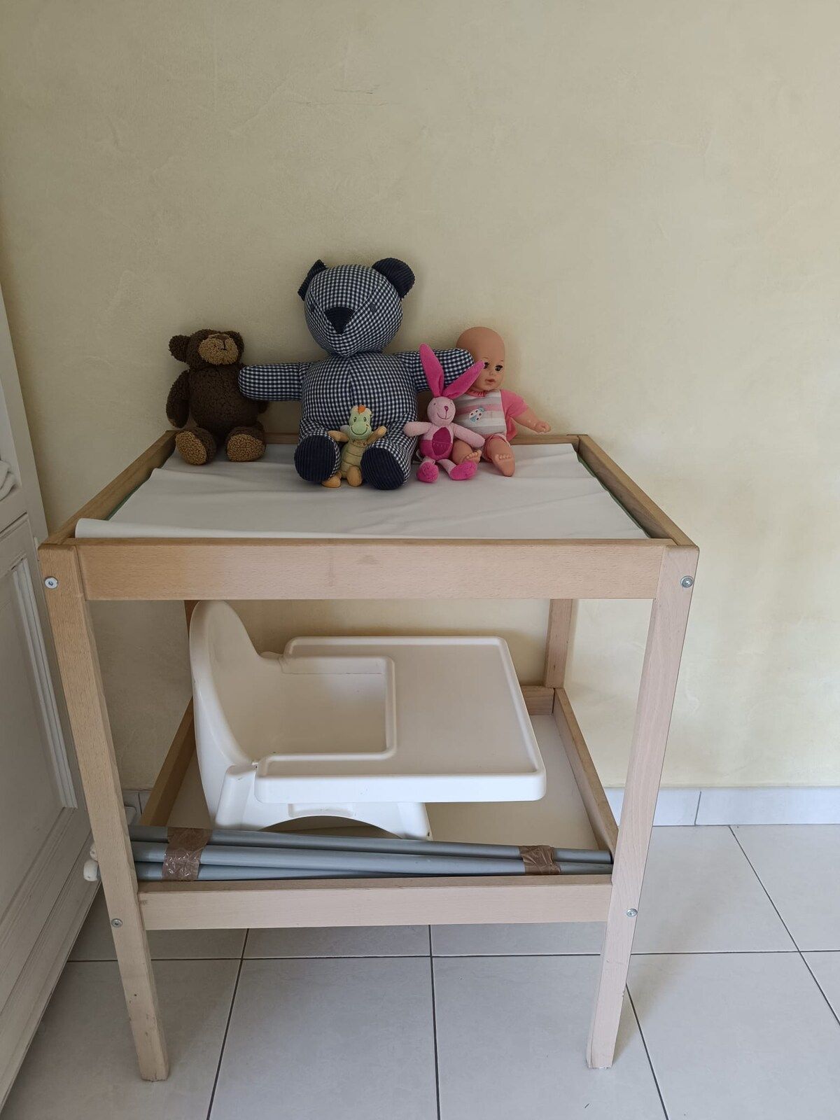 A wooden table with a white tray and a lower shelf, against a plain wall.