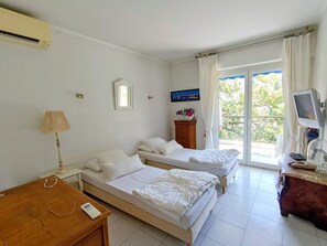 A hotel room with two beds, a desk, a lamp, a television, and a window with curtains. - Swimming pool, 3 bedrooms, baby-friendly (Toulon)