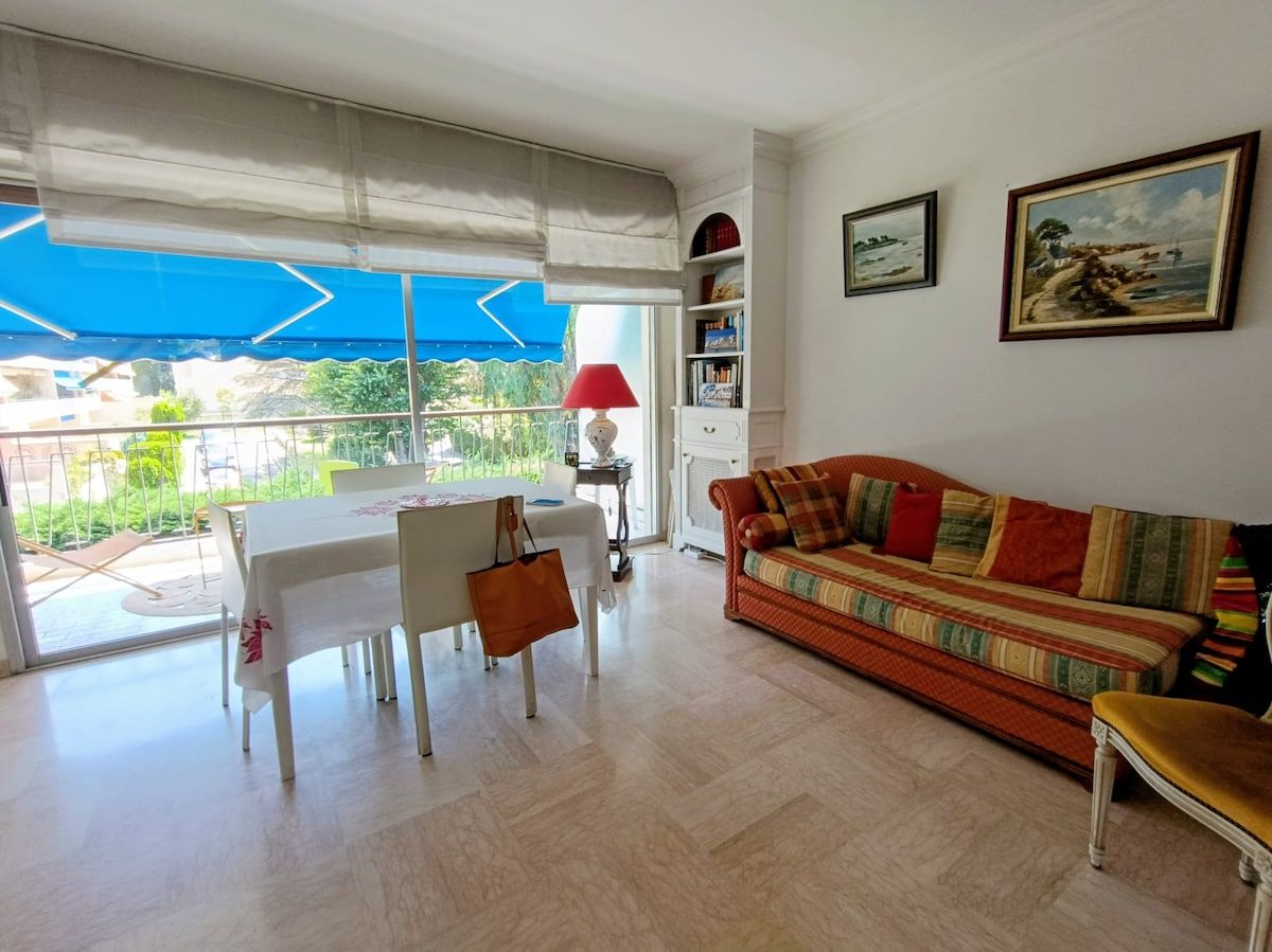 A living room with a sofa, a dining table, and a red lamp.